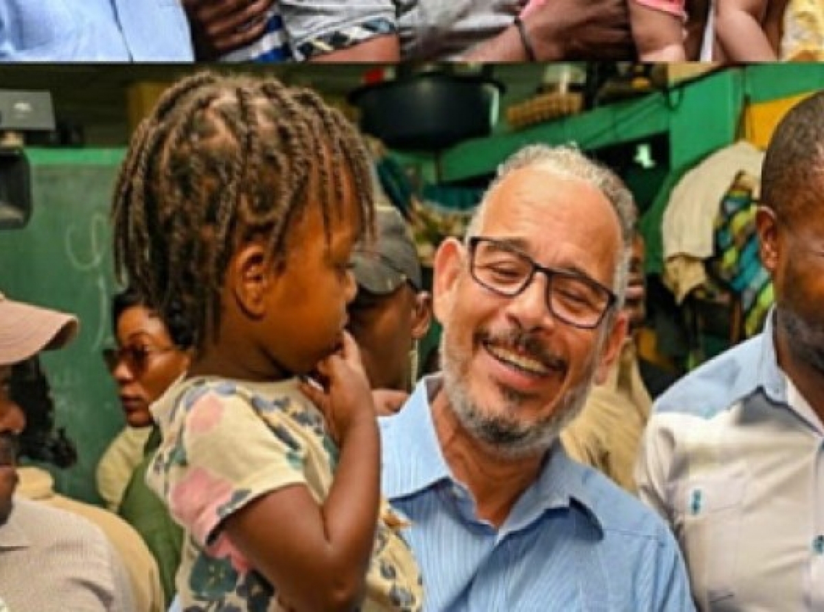 Prime Minister Alix Didier Fils-Aimé , smiles and lifts a child during a visit to a home for people fleeing gang violence over the last weekend.