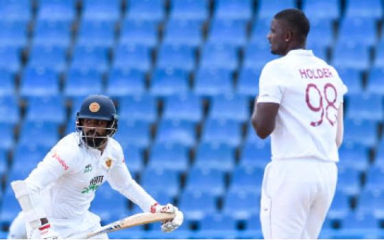 Fast bowler Jason Holder (right) looks on as opener Lahiru Thirimanne gathers runs through the on side during his half-century on Tuesday.