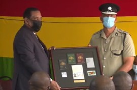 President Charles savarin being handed a souvenir copy of the E-Passport from a senior police officer (CMC Photo)