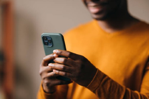 A close up view of an unrecognizable African-American entrepreneur watching something on his smartphone.