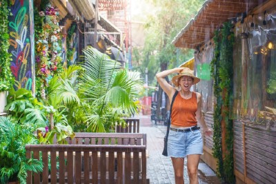 Young woman smiles and laughs under the rain. Girl enjoying warm summer tropical rain