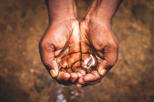 a man holding water with his hand,water crisis in India and worldwide