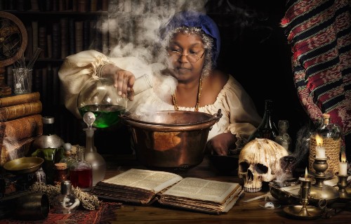 Female alchemist preparing green liquids in a smoking kettle