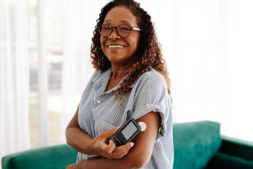 Diabetic woman using a flash glucose monitor to measure her blood sugar levels with a simple scan, allowing her to adjust her diet and medication as needed for optimal health and wellness.