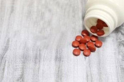 Pills and red knitted heart on wooden table. Concept of antidepressants, hypertension, heart disease, blood pressure