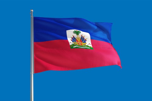 Haiti national flag waving in the wind on a deep blue sky. High quality fabric. International relations concept.