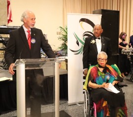 Honoree, former Maryland State Senator Shirley Nathan Pulliam (seated in the wheelchair) listens attentively as Ambassador Curtis Ward pays tribute to her. Also in the photo is the President of the Jamaica Association of Maryland, Mr. Rick Nugent who also paid tribute to the former State Senator who received the Association’s Lifetime Achievement Award. (Photo by Derrick Scott)