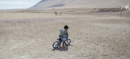 A child rides his bicycle outside a UNICEF-supported humanitarian camp for migrant families in Chile. (Photo courtesy of UNICEF/Pablo Vera-Lisperguer)