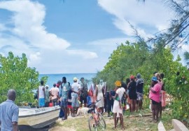 A crowd gathers on the beach after the headless body of student found. He is believed to have been killed by a shark (Jamaica Observer newspaper photo)