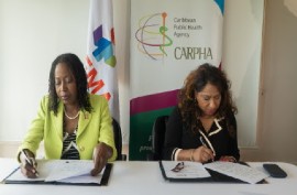 CDEMA Executive Director, Elizabeth Riley and Dr. Lisa Indar, CARPHA Executive Director, sign the agreement for continued partnership.
