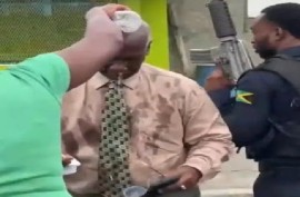 A woman sprays water on the face of Local Government and Community Development Minister, Desmond McKenzie, who had been pepper sprayed while trying to clam protesters on Tuesday