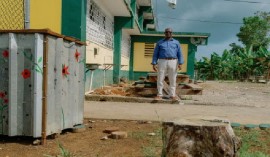 Rohan Green, Principal of the Petersfield High School poses on the school compound with a trash bin created from hurricane Melissa debris