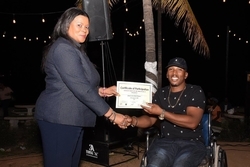 Cosmo Watson, stage name the Real V.I., winner for Amateur Night on the Mound’s Music category receives his award from Daffodil Thompson, Interim Executive Director at the JCDC.