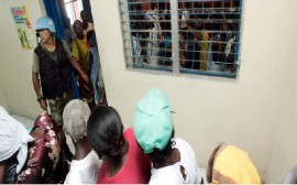 A member of the Peruvian Battalion serving with MINUSTAH guards a facility on the edge of Cité Soleil and Cité Militaire in Port-Au-Prince, Haiti, allowing people to come in and register. (UN Photo)